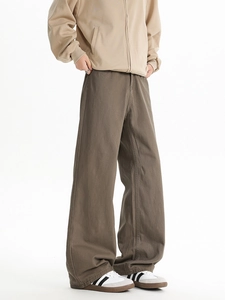 Macro view of wide-leg brown trousers showing twill cotton texture and relaxed drape fit