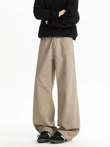 Detail shot of khaki wide-leg casual trousers paired with sneakers on white backdrop