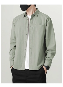 Detail of sage green cotton shirt collar and chest pocket over a white t-shirt