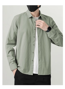 Close-up of light green cotton linen shirt featuring classic collar and buttoned cuffs