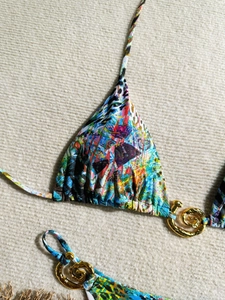 Gros plan d'un bikini à imprimé abstrait avec des détails métalliques dorés de luxe