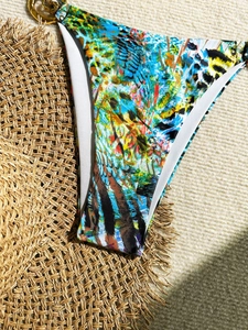 Détail du bas de bikini imprimé abstrait coloré avec un anneau métallique doré chic