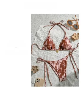 Detail view of floral print bikini with a gold floral pendant and side-tie design