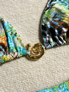 Détail d'un bikini imprimé abstrait multicolore avec un fermoir spirale doré