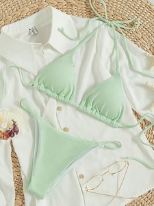 Mint green ribbed triangle bikini set displayed with summer accessories on a straw mat