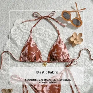 Flat lay of floral bikini set with tropical hibiscus print on soft textured background