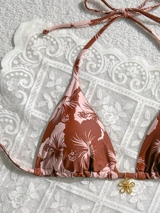 Close-up of pink tropical hibiscus print bikini top with golden flower charm detail
