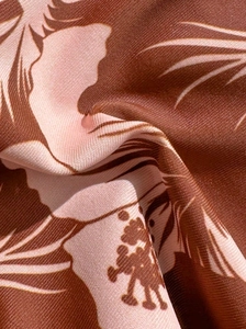 Macro view of tropical hibiscus and palm leaf print fabric on smooth twill swimwear material