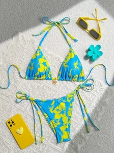 Flat lay of a floral print halter bikini set with blue base and yellow hibiscus pattern