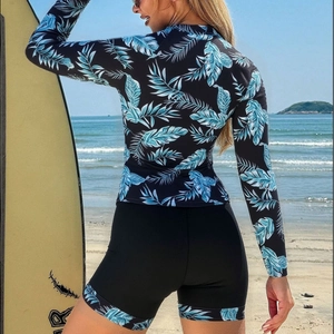 Women's long sleeve two-piece surf swimsuit with palm leaf print on a scenic beach