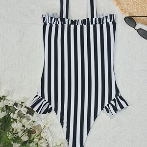 Detailed flat lay of striped one-piece swimsuit with ruffle trim and summer accessories