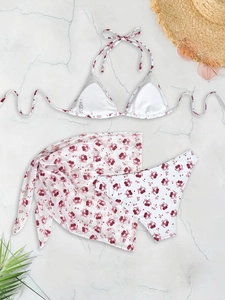Three-piece white bikini set with cherry and bow prints, featuring halter top and matching sarong