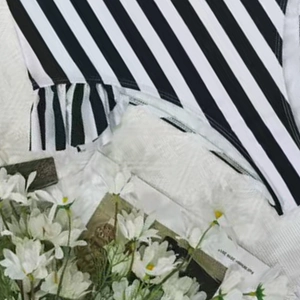 Detailed close-up of black and white striped swimsuit with ruffled frill design edges
