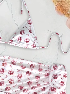Three-piece bikini set with cherry print, halter top and matching cover-up on beach stone