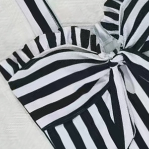 Close-up of black and white striped swimsuit featuring ruffled neckline and bow detail