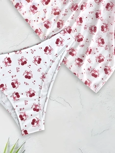 Three-piece white bikini set featuring cherry and bow patterns on marble background