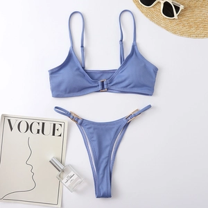 Flat lay of gray-blue ribbed bikini set with gold buckles and summer accessories
