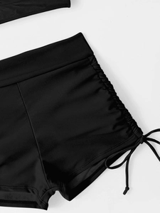 Detail of black high-waist ruched swimming shorts with side drawstring and seamless waist