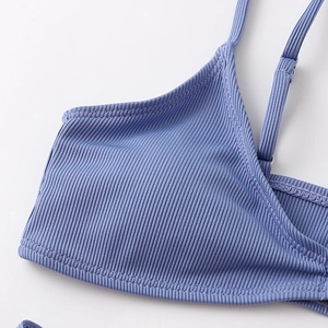 Detail of light blue ribbed bikini top featuring adjustable straps and silver metal buckles