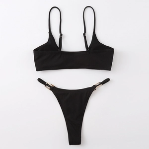 Flat lay of black ribbed bikini set featuring gold buckle accents and adjustable straps