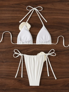 Set bikini bianco a fascia con fiori 3D su sfondo di legno scuro