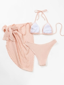 Detailed view of peach pink three-piece bikini set with textured fabric and mesh wrap skirt