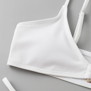 Macro shot of white ribbed bikini top fabric and golden metal shoulder strap adjuster