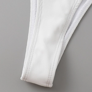 Detailed close-up of white ribbed bikini fabric showing durable double-stitched seams