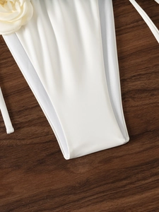 Dettaglio slip bikini bianco con pannelli in rete e decorazione floreale 3D applicata