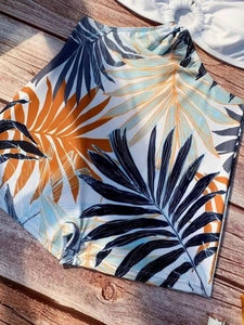 Floral bikini bottom with tropical leaf print and metal ring on wooden background