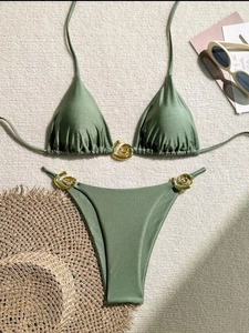 Olive green bikini set with gold metal buckle detail on textured vacation background