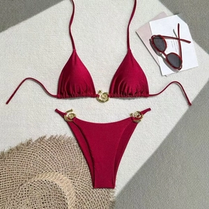 Detail of burgundy bikini set featuring gold swirl metal buckles and high-leg cut style