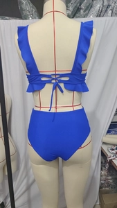 Detailansicht der Rückseite eines blauen Bikinis mit Rüschen und Schnürung am Rücken