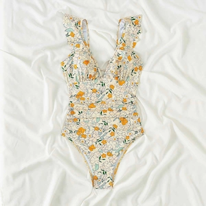 Detail of floral deep V-neck swimsuit with ruffle straps on white silk background