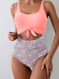 Detail of high waist swimsuit featuring coral pink top and black polka dot pattern prints