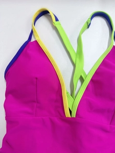 Détail du décolleté en V avec bordure néon et bretelles croisées sur un maillot de bain rose