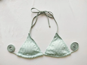 Detail of mint green bikini top featuring textured ribbed fabric and neck ties