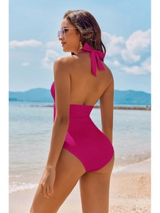 Sexy magenta one-piece halter swimsuit with backless design and bowknot on beach