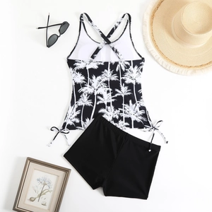 Flat lay of a palm tree print tankini set with boy-leg shorts and vacation accessories
