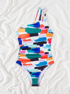 Flat lay of one-piece swimsuit featuring colorful brushstroke prints and cut-out shoulder detail