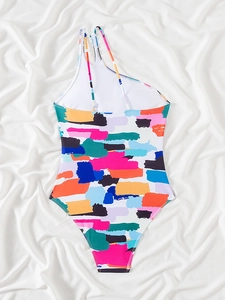 Detail view of one-piece swimsuit with vibrant abstract graffiti and asymmetric shoulder