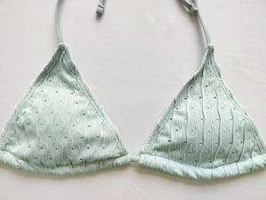 Close-up of mint green bikini top with textured rib knit fabric and hollowed detailing