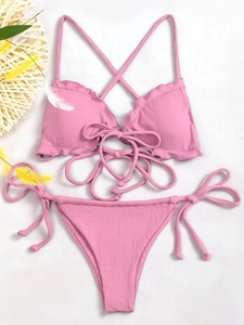 Detail of pink ribbed bikini set with ruffled edges, halter neck tie, and side-tie bottoms