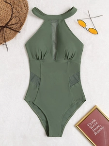 Detail of dark green one-piece swimsuit featuring mesh patchwork and pleated texture
