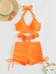 Flat lay of bright orange two-piece bikini with halter neck top and side-tie shorts