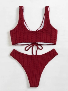 Detailed macro shot of burgundy ribbed bikini set featuring textured bubble fabric and lace-up hem