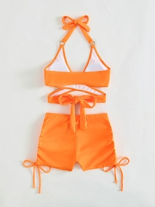 Detail of high-waisted bikini shorts with adjustable side drawstrings in bright orange