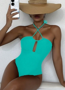 Detail of teal halter neck swimsuit with cutout design and elegant beach accessories