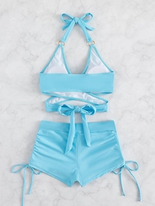 Detail of light blue two-piece swimsuit with halter neck ties and side drawstring shorts