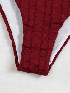 Macro view of burgundy ribbed texture fabric and white lining of the bikini bottom